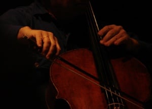Image shows someone playing the cello; only their hands and the cello are visible. 