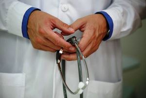 Image shows someone wearing a lab coat, holding a stethoscope. 