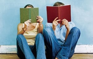 Image shows a couple sat side-by-side, both reading.