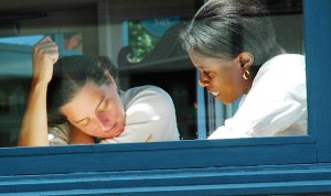 Image shows a student and a teacher working together, seen through a window.