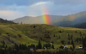 Image shows a rainbow against mountains.