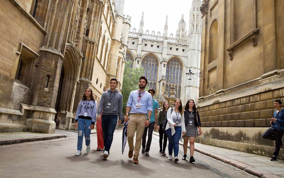 students walking through a small street in front of the King's College, Cambridge